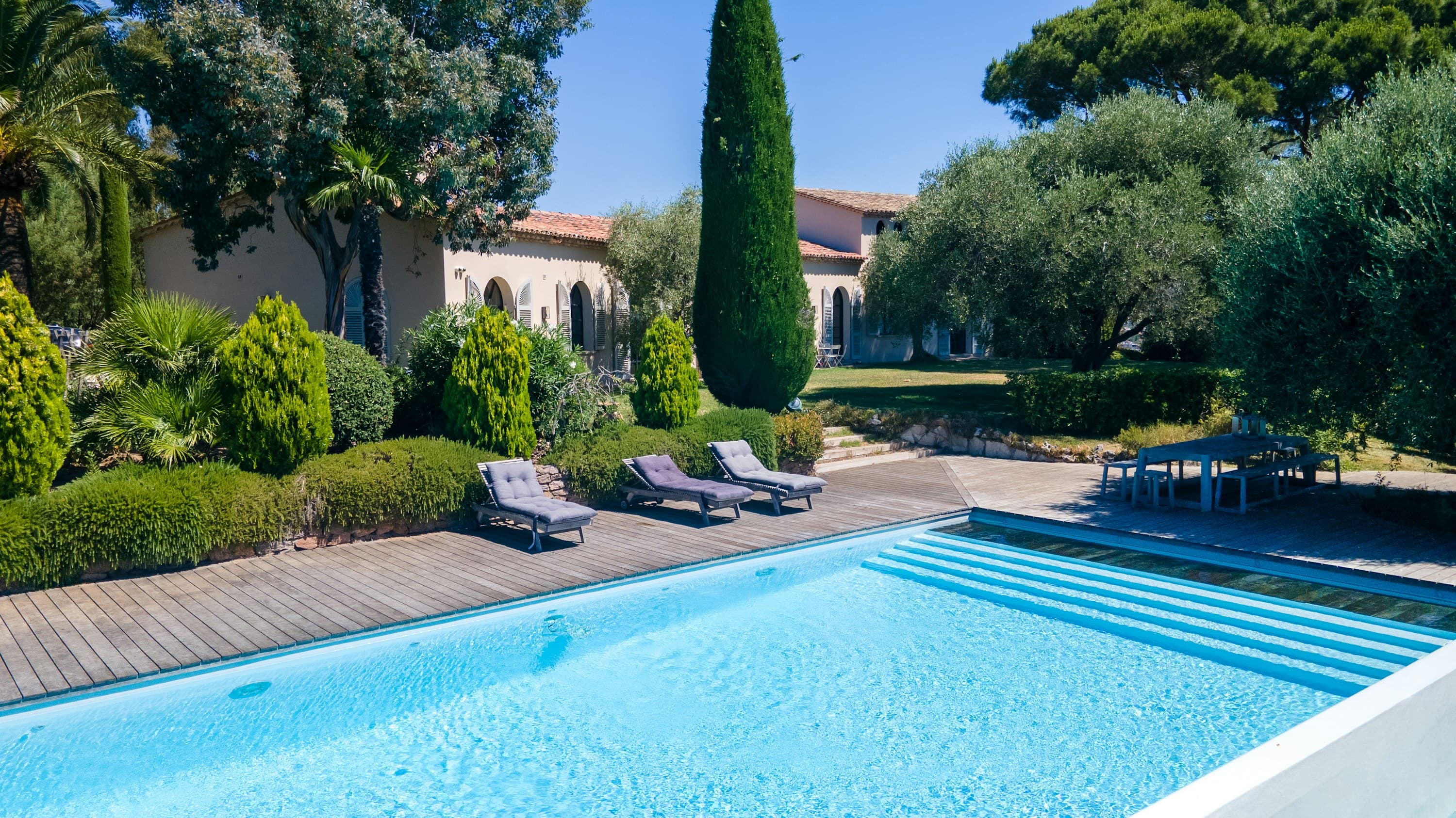 An Azure Vision villa exterior with striped pool and cypress gardens, Cannes, French Riviera, France